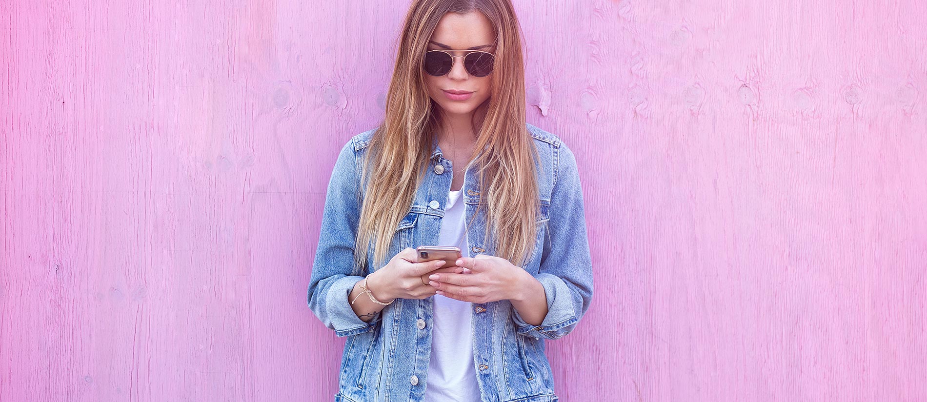 Woman with mobile phone with pink backdrop