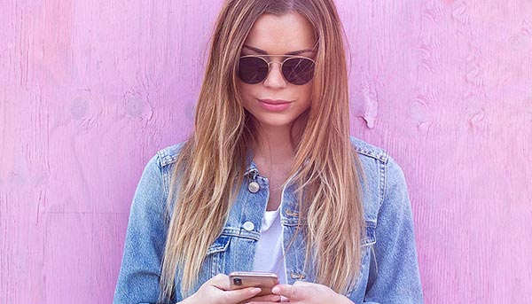 Woman with mobile phone with pink backdrop