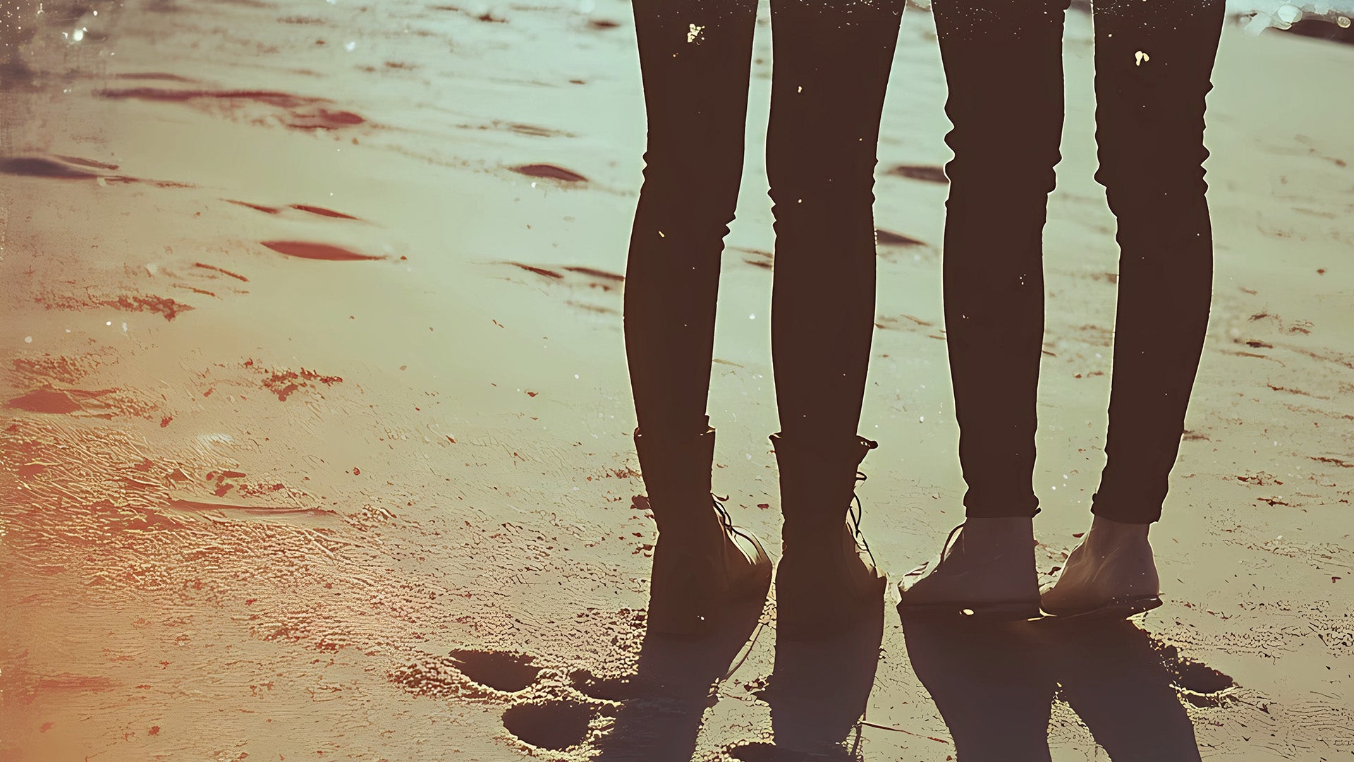 Image of a couple of people on the beach at sunset wearing skinny jeans.