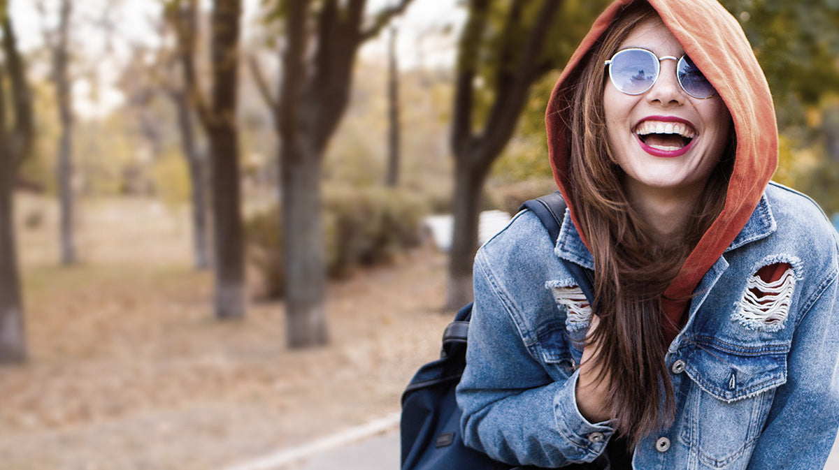 Photo of woman wearing a hoodie and denim jacket.